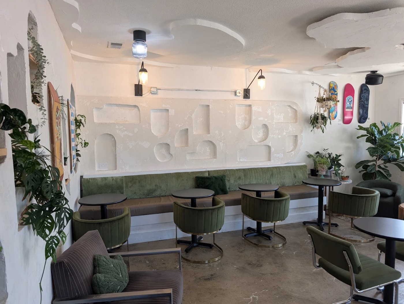 Cozy front seating area with green velvet chairs, plants and skateboards